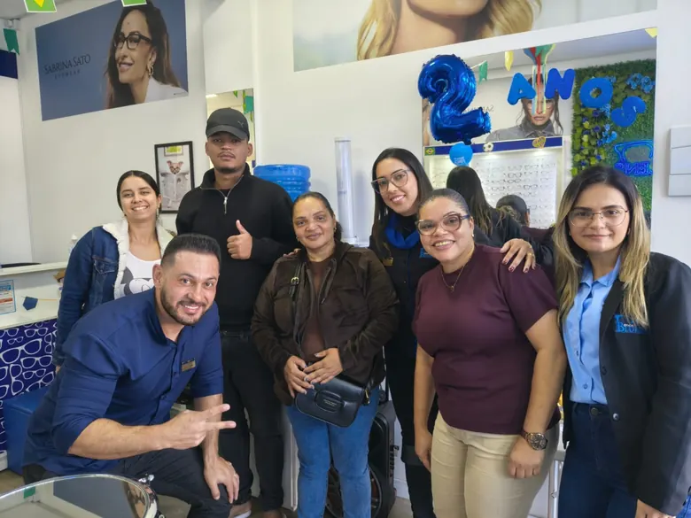 Grupo de clientes e equipe da Blulens reunidos dentro da loja